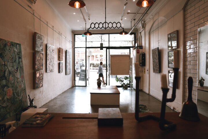 Gallery space with artworks on brick walls and a glass shopfront