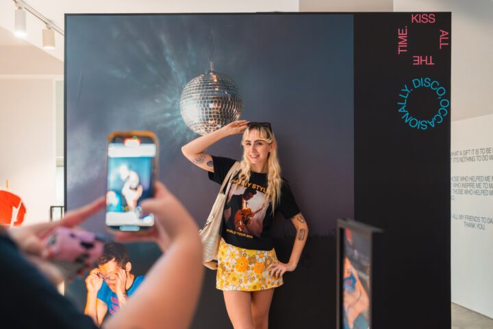 A fan posing at the disco-ball photo installation inside the Harry Styles Sydney pop up